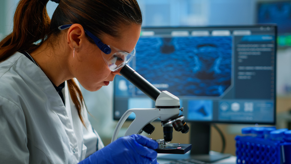 Mujer con microscopio y ordenador